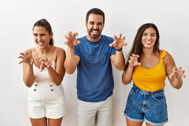 Skupina mladých hispánských lidí stojící nad izolovaným pozadím s legračním úsměvem dělá drápy gesto jako kočka, agresivní a sexy výraz  - Fotografie, Obrázek