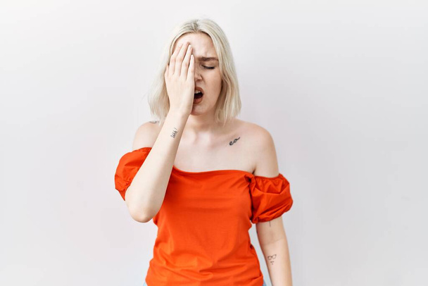 Young caucasian woman standing over isolated background yawning tired covering half face, eye and mouth with hand. face hurts in pain.  - Foto, Imagem
