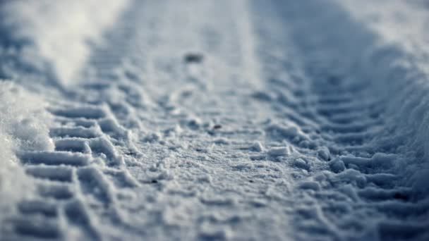 Segno di ruota sulla superficie della neve durante la gelida giornata invernale da vicino. Modello di pneumatico auto impresso su strada innevata. Strada rurale vuota coperta di neve bianca ghiacciata primo piano. Paesaggio suburbano invernale. - Filmati, video