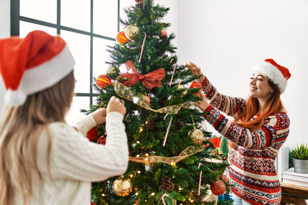 Ehepaar lächelt selbstbewusst beim Schmücken des Weihnachtsbaums zu Hause - Foto, Bild