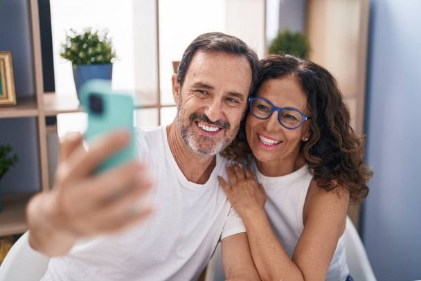 Man and woman couple make selfie by smartphone sitting on table at home - Foto, imagen