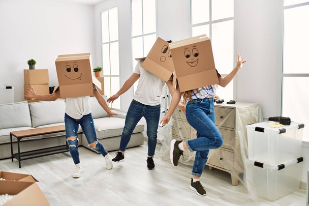 Mère et couple jouent avec une drôle de boîte en carton sur la tête à la maison - Photo, image