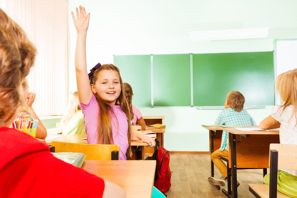 Girl holds hand up in classroom - Valokuva, kuva