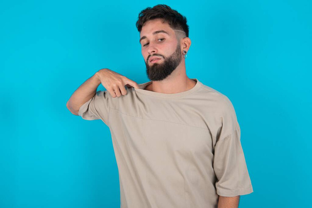 bearded caucasian man wearing casual T-shirt over blue background stressed, anxious, tired and frustrated, pulling shirt neck, looking frustrated with problem - Photo, Image