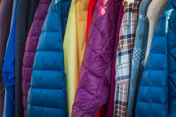 Řada podzimních kabátů visících na stojanu, nakupování. Obchod s látkami, obchod s oblečením, dámská a pánská kolekce v módním butiku. Nikdo, selektivní zaměření - Fotografie, Obrázek