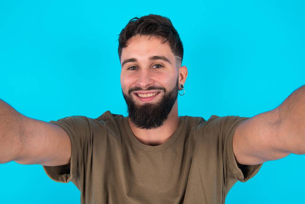 Fénykép fiatal spanyol szakállas férfi ellen kék háttér do selfie - Fotó, kép