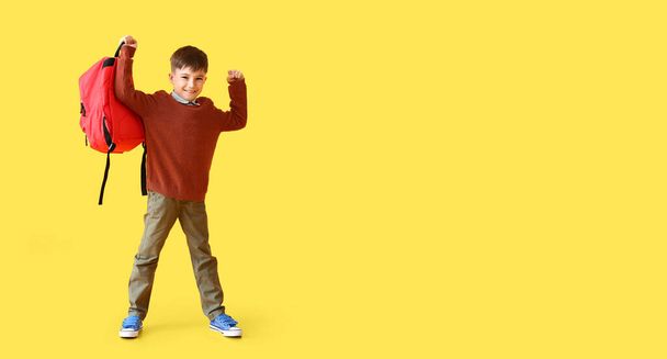 Little schoolboy holding backpack on yellow background with space for text - Photo, image