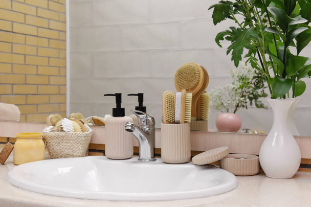 Kylpyamme tarvikkeet, pesuallas ja maljakko kasvi oksat pöydällä kylpyhuoneessa - Valokuva, kuva