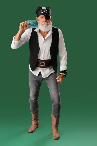 Alter Pirat mit Flasche Rum auf grünem Hintergrund - Foto, Bild