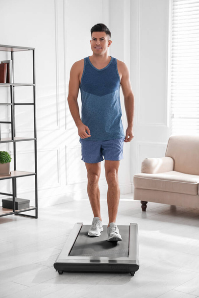 Sportlicher Mann trainiert zu Hause auf Laufband - Foto, Bild