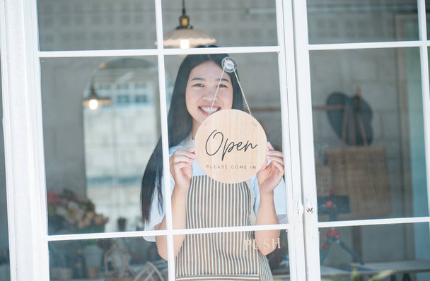 Smiling online small business owner holding a sign saying "Open" and happily working at a courier business offering orders and products to customers.Online retailer - online shopping. - Foto, Bild