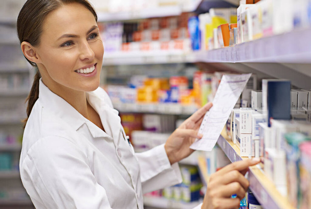 Finding the best treatment possible. an attractive young pharmacist collecting a prescription in an aisle - Foto, Imagem