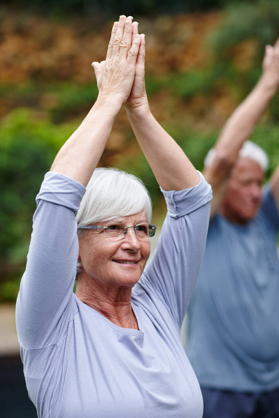 Verbesserung ihrer Gesundheit und ihres allgemeinen Wohlbefindens. eine Seniorin beim Yoga mit ihrem Mann im Freien - Foto, Bild