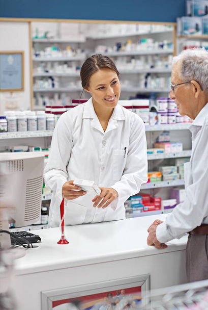 Ze zorgt er altijd voor dat klanten hun medicijnen weten. een jonge apotheker die een oudere klant helpt aan de receptenbalie - Foto, afbeelding
