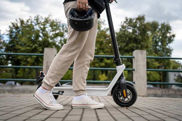 昼間の舗装上の電動キックスクーター電子スクーターを立っているか、または運転未知の男の足環境に優しい近代的な輸送 - 写真・画像