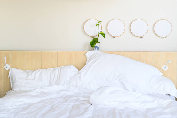 Wit beddengoed met plantaardige decoratie in minimale hotelkamer. - Foto, afbeelding