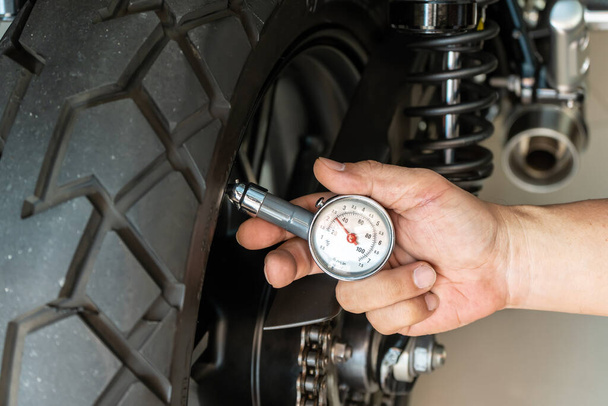 Manómetro de retención de hombre para comprobar la presión de los neumáticos de motocicleta, mantenimiento, concepto de motocicleta de reparación en el garaje .focu selectivo - Foto, imagen