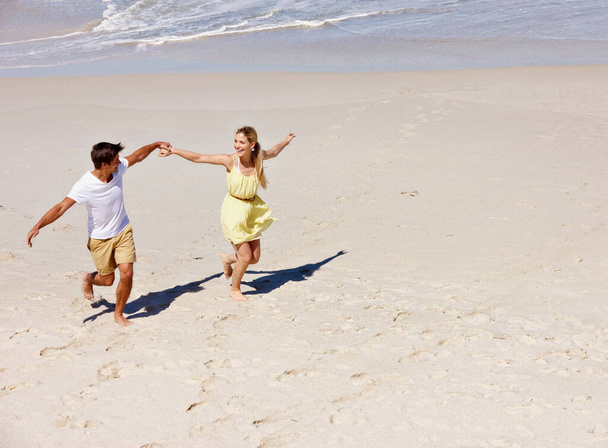 Nyaralás közben a legboldogabb. egy boldog fiatal pár élvezi a romantikus séta a strandon - Fotó, kép