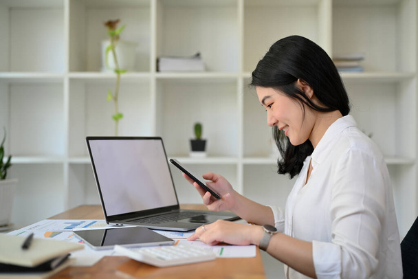 Красивая азиатская бизнесвумен или женщина-бухгалтер, работающая в офисе, анализируя отчеты по продажам. - Фото, изображение