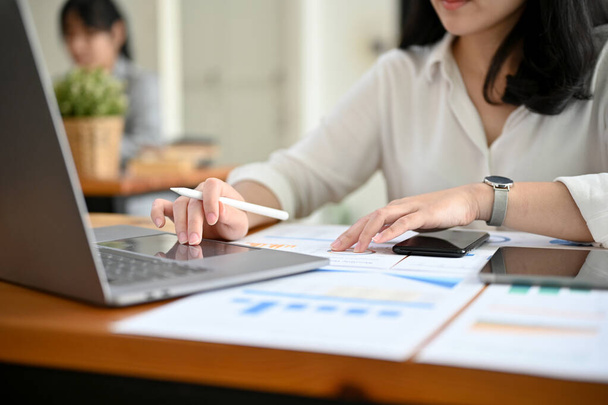 Успешная деловая женщина или финансовый аналитик, работающая за своим рабочим столом, используя ноутбук для анализа финансовых данных. обрезанное изображение - Фото, изображение