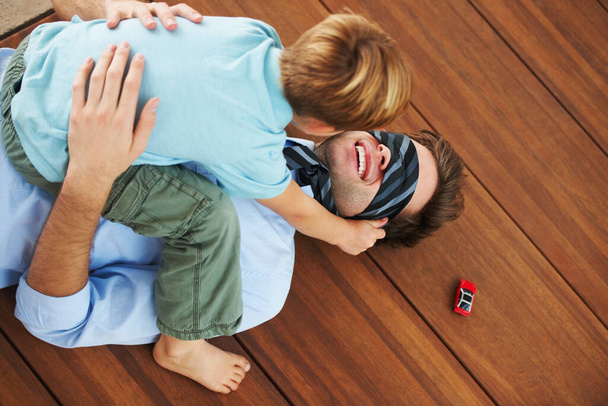 So glad Dads home. A little boy playing with his father on the floor - 写真・画像