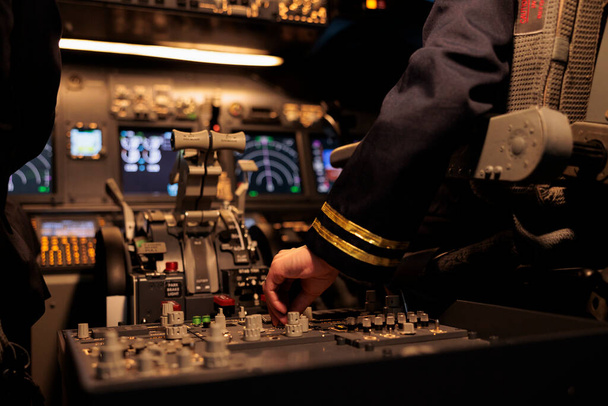 Członek załogi używający polecenia panelu sterowania na desce rozdzielczej do pilotowania samolotu w kokpicie. Samolot samicy w kabinie z silnikiem mechanicznym i dźwignią przełączającą. Zamknij się.. - Zdjęcie, obraz