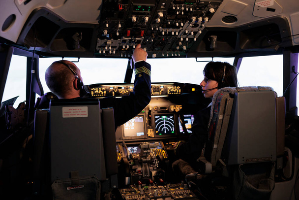 Captain and copilot using dashboard command to takeoff with plane, flying aircraft with control panel switch and buttons. Radar handle in aircrew cabin to fly airplane with windscreen. - Photo, Image