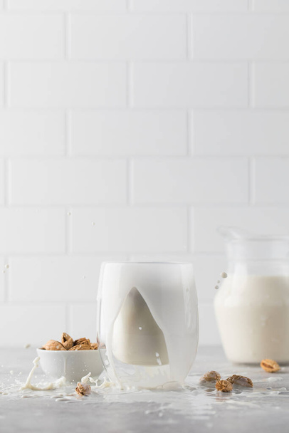 Splash in a mug with vegetable almond milk on a light background. The concept of a healthy lifestyle. Alternative to dairy products  - Фото, изображение