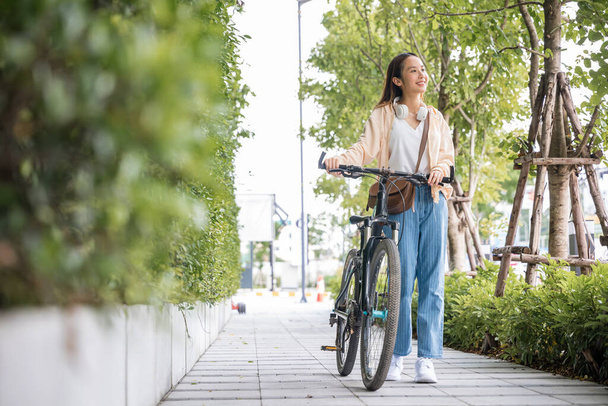 Happy female smiling walk down the street with her bike on city road, ECO environment, healthy holiday travel, Asian young woman walking alongside with bicycle on summer in park countryside outdoor - Φωτογραφία, εικόνα