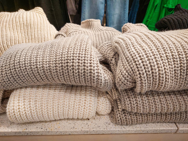 Empiler des pulls pliés dans le magasin de vêtements. Pulls tricotés pour la saison froide d'automne et d'hiver. Automne, vêtements d'hiver. Personne, photo mobile - Photo, image