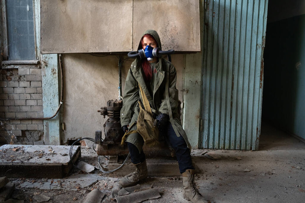 Post apocalyptic female survivor in gas mask, destroyed building in the background. Copy space - Photo, Image