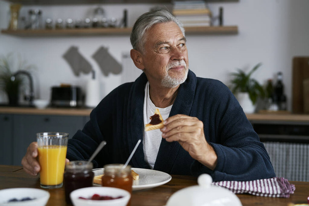 Homme caucasien senior manger le petit déjeuner à la maison  - Photo, image