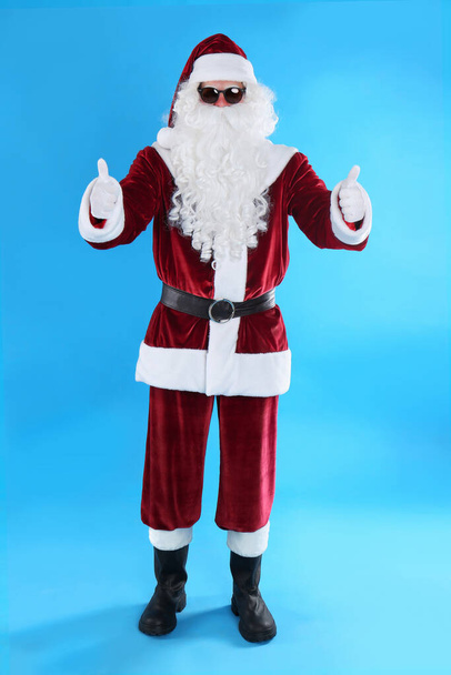 Full length portrait of Santa Claus with sunglasses on light blue background - Φωτογραφία, εικόνα