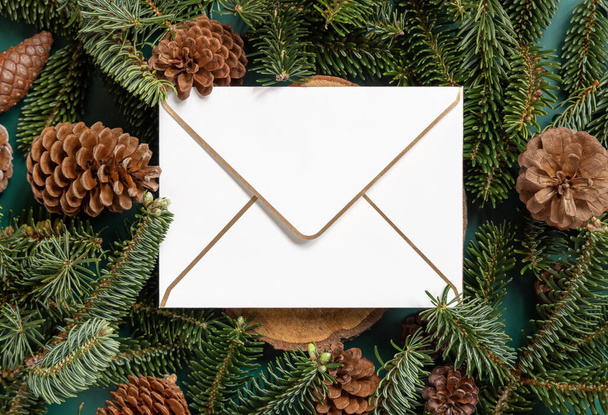 blank envelope between fir branches and pine cones on green top view, mockup. Christmas or New Year greeting envelope template, Holiday winter composition - Φωτογραφία, εικόνα