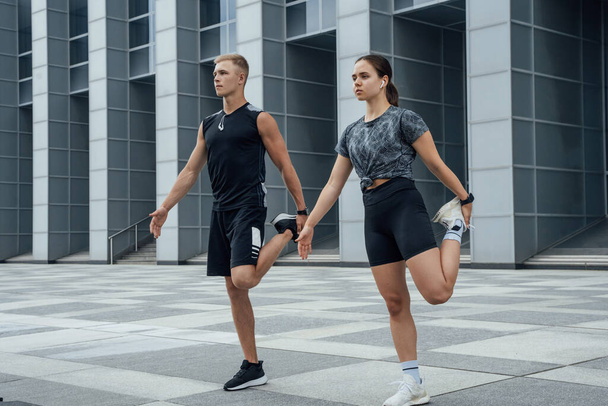 Shot of sportsman and sportswoman warming up together preparing to running in city. - 写真・画像