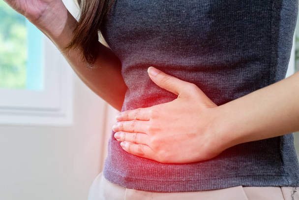 woman hand touching abdomen having stomach ache, female eating food poisoning causes flatulence, digestive disease, Abdominal pain during menstruation. - 写真・画像