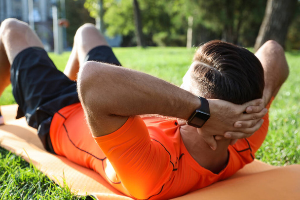 Man wearing fitness tracker during training in park - Foto, Bild