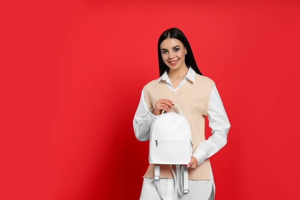 Young woman with stylish backpack on red background. Space for text - Фото, зображення