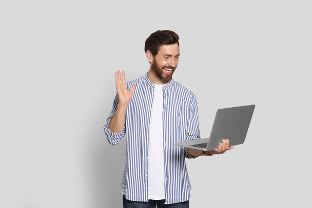 Emotional bearded man with laptop on light background - Photo, Image