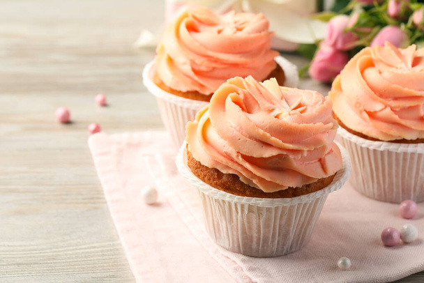 Tasty cupcakes with cream on wooden table, closeup - Photo, image