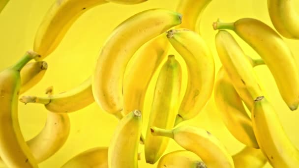 Super Slow Motion Shot de plátanos frescos sobre fondo amarillo volando hacia la cámara a 1000fps. Filmado con cámara de cine de alta velocidad a 4K. - Metraje, vídeo