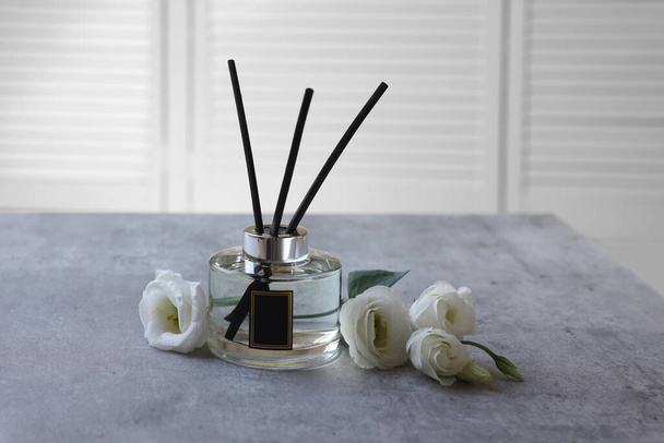 Reed diffuser and eustoma flowers on gray marble table - Photo, image