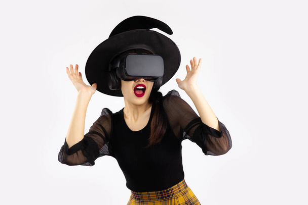 Metaverse concept and halloween theme young asian woman in black shirt wearing vr goggles glasses posing surprising exciting watching and playing on white background. - Fotografie, Obrázek