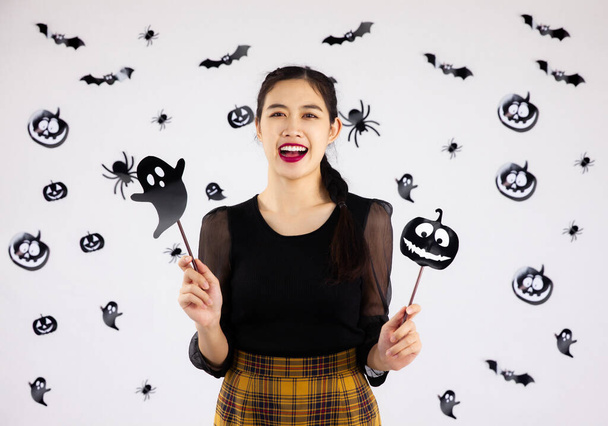 Halloween téma, mladá hezká asijská žena v černých šatech pózovat šťastný na černošky monster grafika na bílém pozadí. - Fotografie, Obrázek