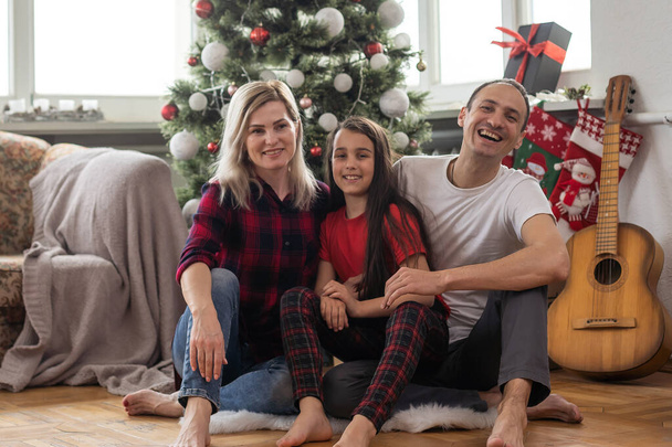 Молодая счастливая семья во время празднования Рождества дома
 - Фото, изображение