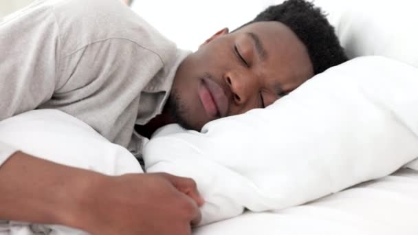 Sleep, relax and dream for a black man home in bed on a weekend morning. Tired, sleeping and dreaming in bedroom alone. Relaxing, peace and comfort with head on pillow for sleepy time in bright room - Metraje, vídeo