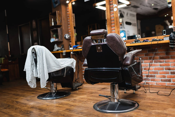comfortable hairdressing armchairs near mirrors in modern barbershop - 写真・画像