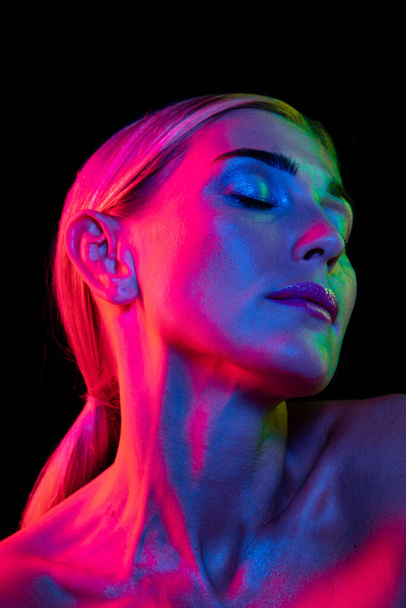 Passion. Beauty portrait of young adorable woman with well-kept skin isolated over dark background in pink neon light. Concept of art, fashion, style, inspiration, emotions. Copy space for ad - 写真・画像