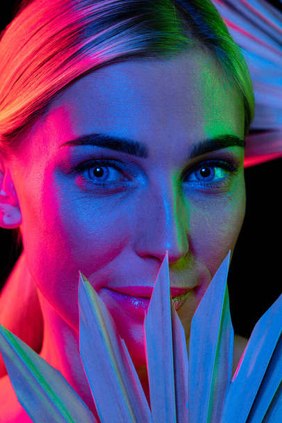Feeling and emotions. High fashion model in colorful bright neon lights posing at studio. Portrait of beautiful woman with glowing make-up. Art design vivid style. Spa, cosmetics, beauty procedures - Foto, imagen