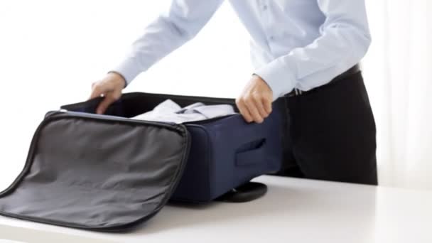 businessman packing clothes into travel bag - Materiaali, video